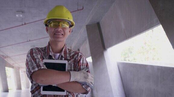 亚洲建筑工程师戴安全帽手持平板电脑在施工现场工程师在现场检查建筑施工项目看着摄像机