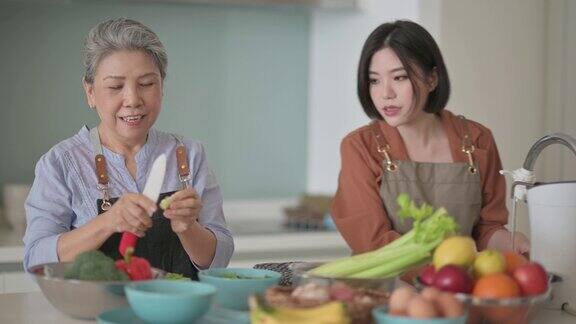亚洲华人美丽的女人和她的母亲准备做饭为家人在厨房柜台