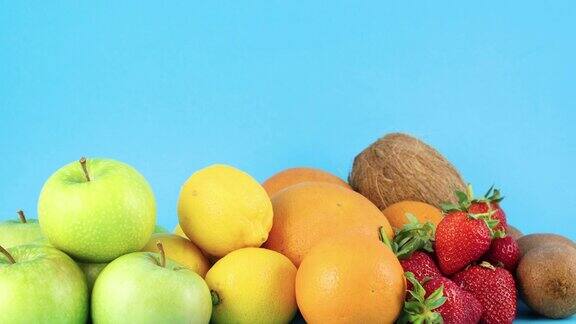 新鲜的苹果柠檬橙子草莓猕猴桃和椰子在蓝色的背景