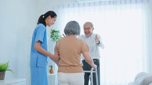 亚洲老年妇女与照顾者和丈夫一起做物理治疗有魅力的专业护工妇女帮助和支持年长的成熟女性病人在养老院练习走路