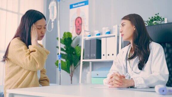 亚洲女性患者到年轻医生处就诊并咨询健康问题有吸引力的治疗师在办公室医院工作解释诊断在预约期间给生病的女孩治疗