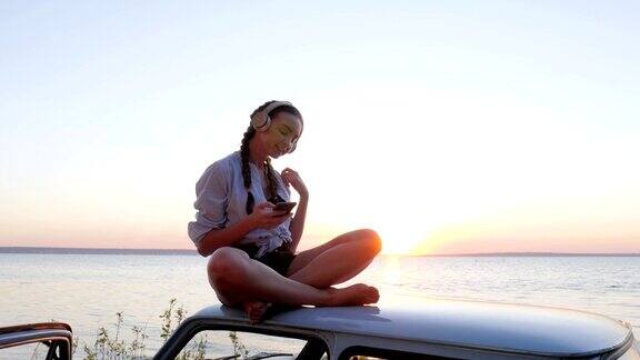 快乐的旅程夏日海滨休息的乐趣女孩在河岸边的车顶上欣赏音乐