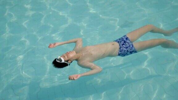 快乐的亚洲男孩回来漂浮在游泳池期间在酒店或度假胜地的家庭生活理念