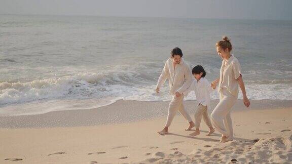亚洲家庭牵着手走在日落的海滩上