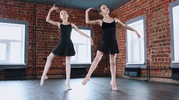 室内芭蕾舞两个穿着黑色套装的体操小女孩在训练中同步跳舞