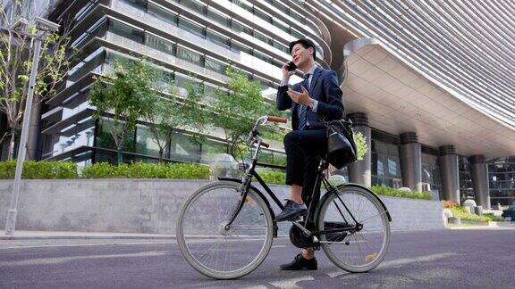 一个年轻的商人骑着自行车用手机打电话