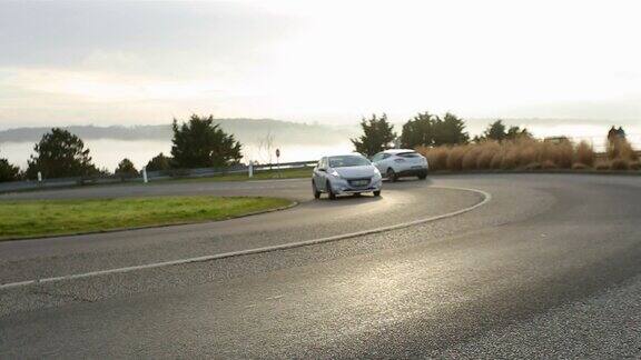 在法国诺曼底地区沥青弯曲的道路上过往的汽车风景如画的乡村风景