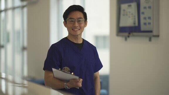 亚洲男护士站在医生办公室前微笑着看着镜头