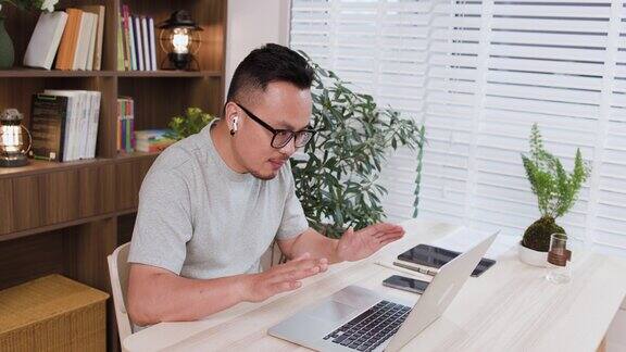 亚洲中年男性在家里用笔记本电脑进行视频会议