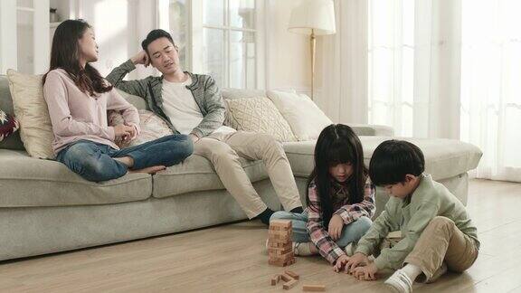 亚洲孩子在父母在家聊天时玩积木