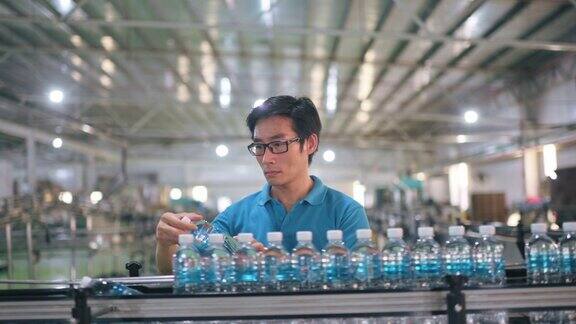 亚洲华人男灌装厂矿泉水饮水厂生产线工人检查水瓶