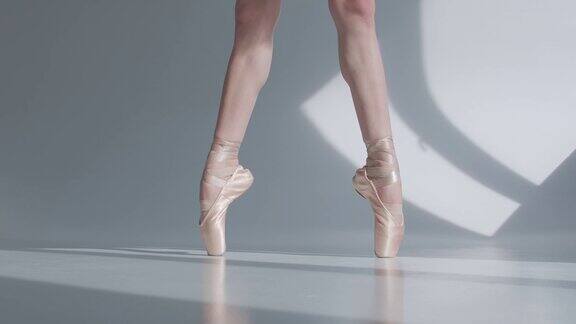 芭蕾舞女演员在跳芭蕾舞脚尖系着丝带白色背景的特写慢动作