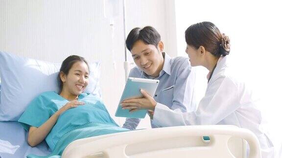 可爱的亚洲夫妇兴奋的父母看超声图像的数字平板电脑在病房