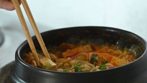 韩国辣面汤泡菜豆腐和蘑菇煮在韩国石碗吃筷子