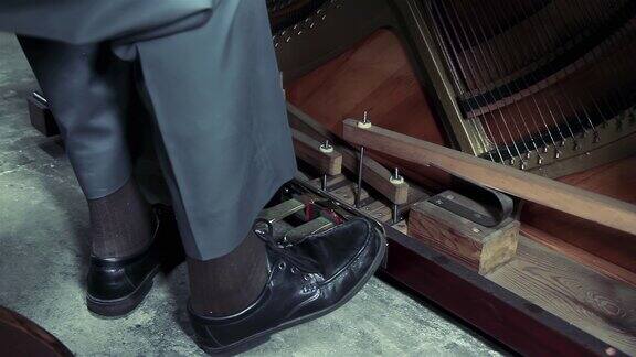 穿着黑鞋的老人的脚踩在一架旧钢琴的钢琴踏板上近距离4K分辨率