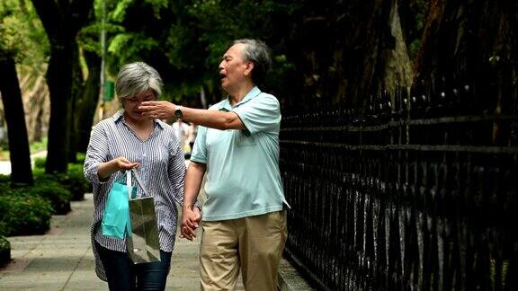 一对老夫妇手牵着手在公园散步