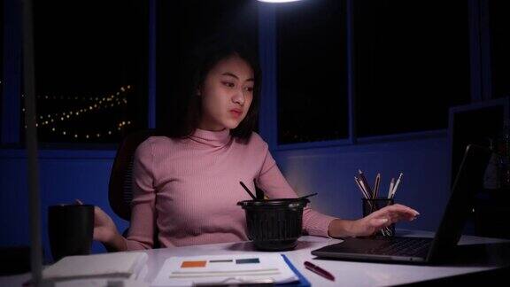 亚洲的女企业家们在晚上的视频会议上一边吃着方便面一边用笔记本电脑工作