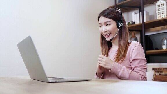 漂亮的女人在家里用笔记本电脑工作亚洲女商人在家里通过视频在线会议