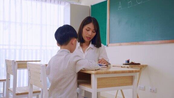 亚洲美女女老师在教室里教小男生在幼儿园有魅力的女教师在课堂上给孩子们讲解和教育课程