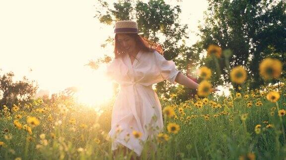 美丽的年轻女子在夕阳下的黄花草地上奔跑