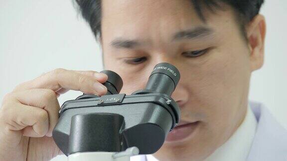 在实验室里通过显微镜观察医学研究的科学家