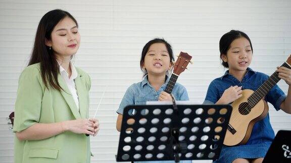 在一所音乐学校一位美丽的亚洲老师正在教学生演奏音乐和唱歌教育孩子的发展