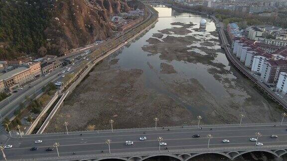 航拍无人机降落因为它飞过大桥在日落干涸的河流