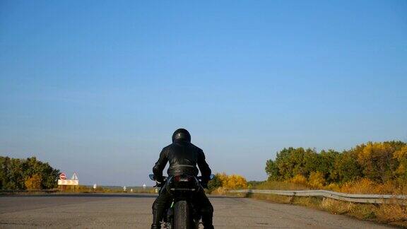 后视图不认识的摩托车在头盔和皮夹克是坐在高速公路上的摩托车准备骑男人要骑摩托车自由和冒险近距离