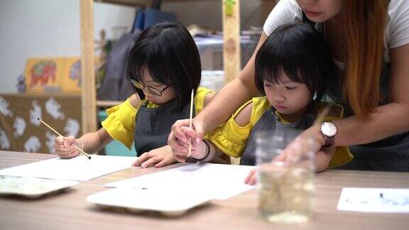 美术班老师在美术工作室教亚洲华人儿童绘画