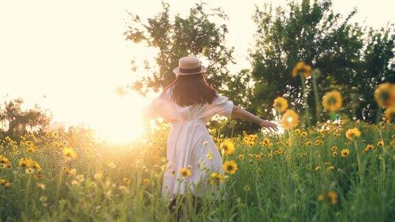 美丽的年轻女子在夕阳下的黄花草地上奔跑
