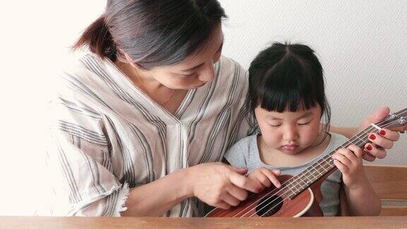 母亲和女儿在家里弹奏尤克里里