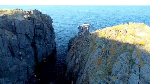 正在上升的无人机拍摄到人们从悬崖上跳入海水中
