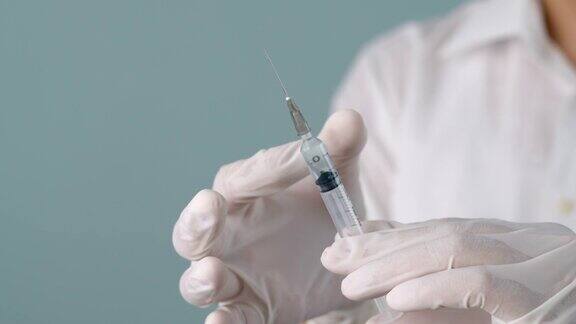 手握注射器疫苗的医生的特写
