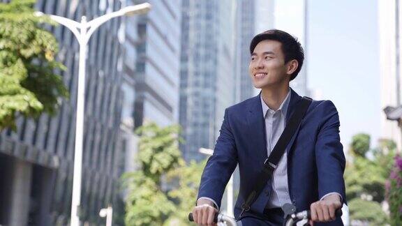 年轻的亚洲商人在现代化的城市里骑自行车上下班