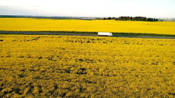 油菜籽田附近高速公路上卡车的鸟瞰图