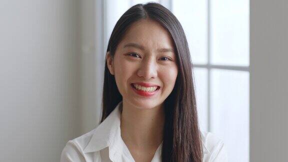 年轻的亚洲女商人的肖像在白色衬衫在办公室工作看着相机和微笑