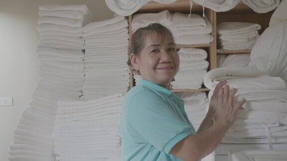 在酒店洗衣店装洗衣机的女工在洗衣店工作的妇女员工在工业洗衣机中装载衣物