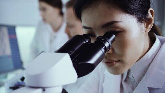 实验室小组处理病原体样本亚洲女医生使用显微镜