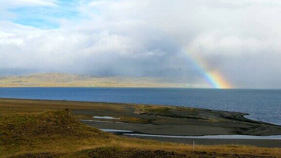 美丽的彩虹在冰岛峡湾在晴朗的日子低雨云和阳光
