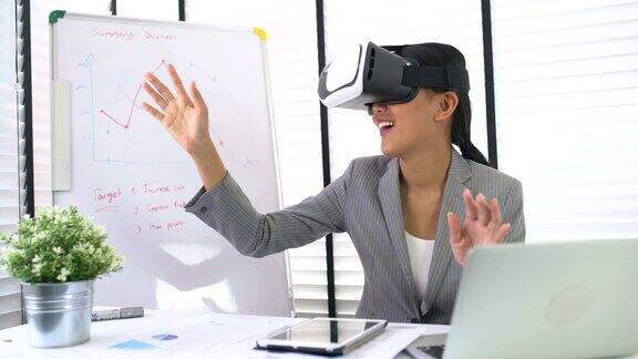 创造性的年轻开发人员在她的办公桌上使用虚拟现实眼镜在办公室