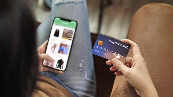 手里拿着信用卡的女人用智能手机在线购物