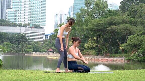 两个年轻美丽的健身亚洲妇女练习瑜伽一起放松在城市公园