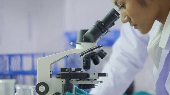 亚洲女性医学研究科学家在实验室通过显微镜观察