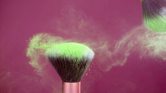 化妆刷与粉红色背景上的绿色粉末爆炸超级慢动作