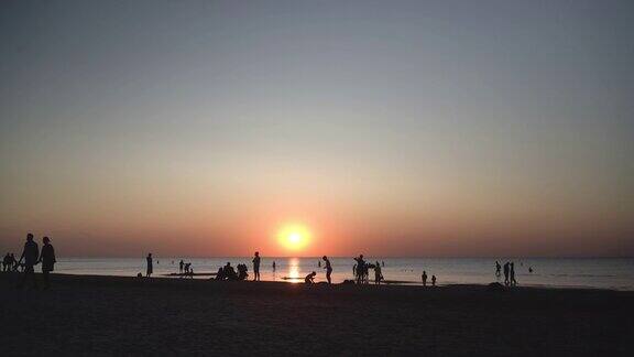 日落时人们沿着海滩散步