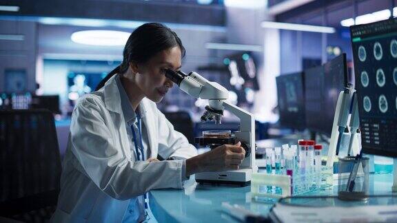 医学发展实验室:亚洲女科学家用显微镜分析培养皿样品大型制药实验室与专家进行生物技术研究开发新药