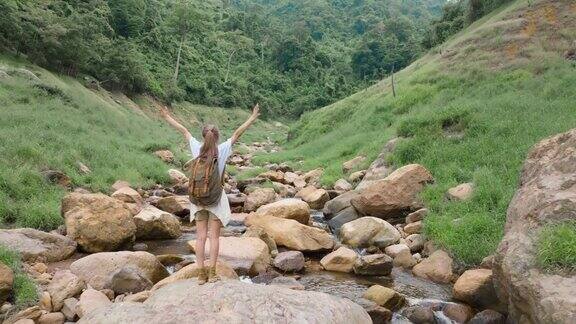 年轻的亚洲旅行者女人站在岩石上庆祝成功的徒步旅行