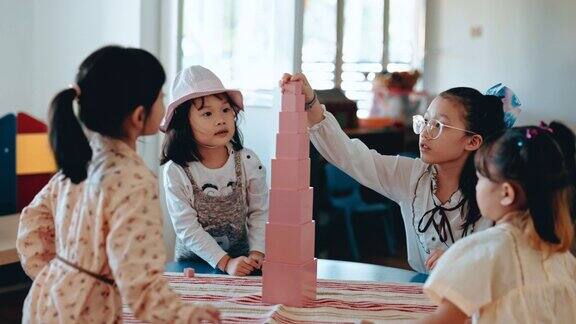亚洲华人前酷女孩完成最后一块玩具积木建筑塔在蒙特梭利教室