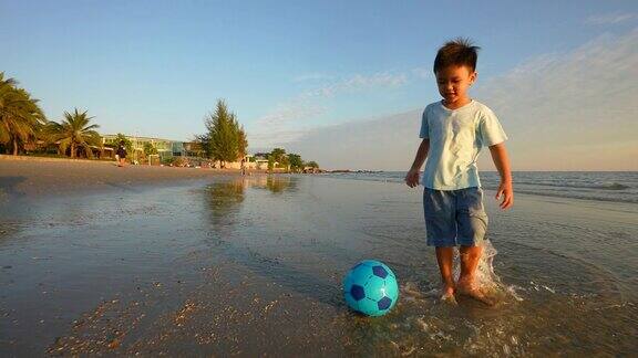 亚洲小孩在沙滩上踢足球假期和健康