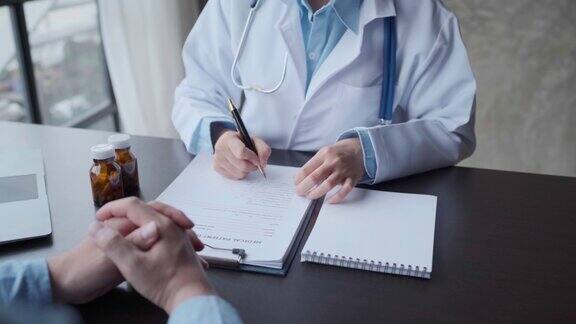 医生和病人在医院办公室体检时坐着聊天特写治疗师填写用药历史记录医药保健理念